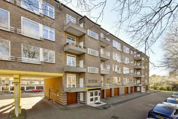 Appartementengebouw aan de Cornelis Dopperkade met meerdere balkons, garages en geparkeerde auto's langs de straat.